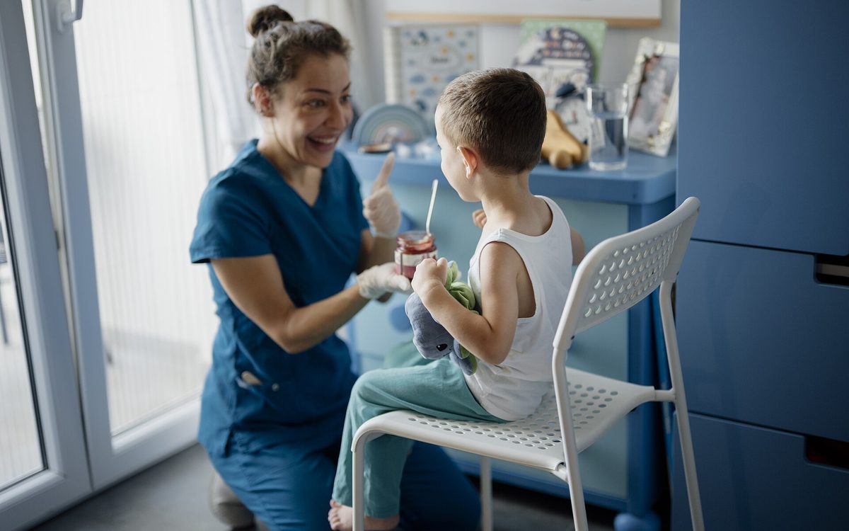 A smiling dental nurse treating a young patient in a clinic