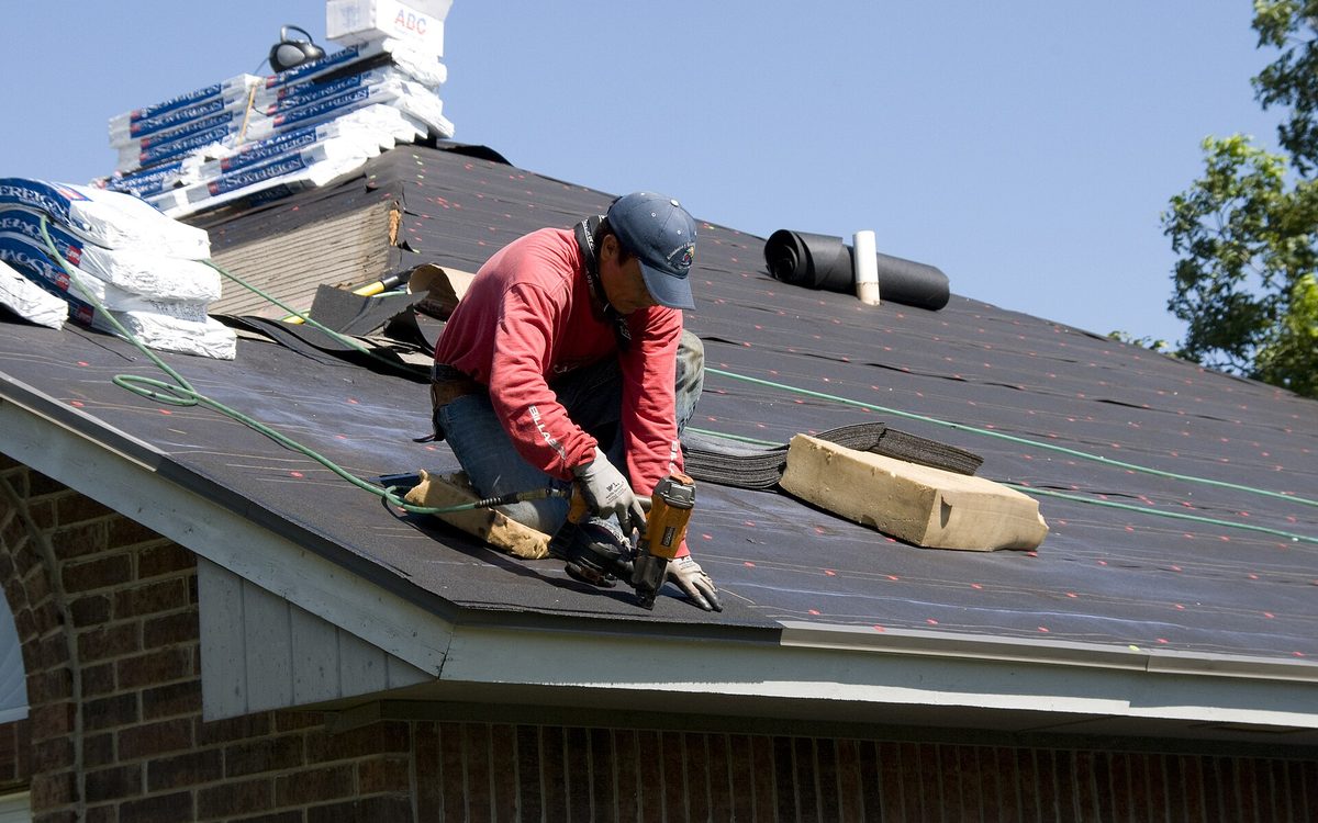 A roofer fitting roofing felt on a house roof